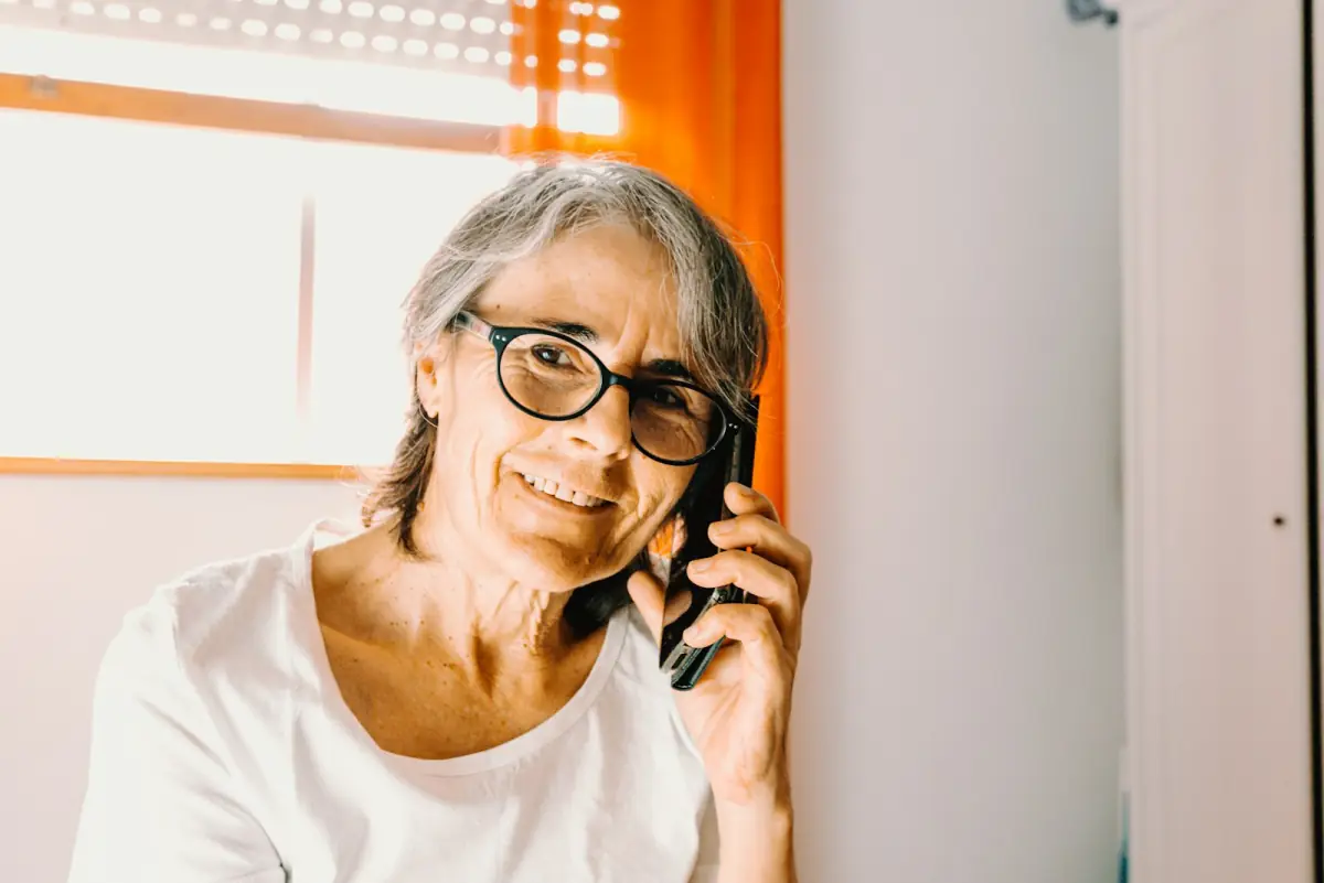 Señora mayor hablando por teléfono, sonriendo.
