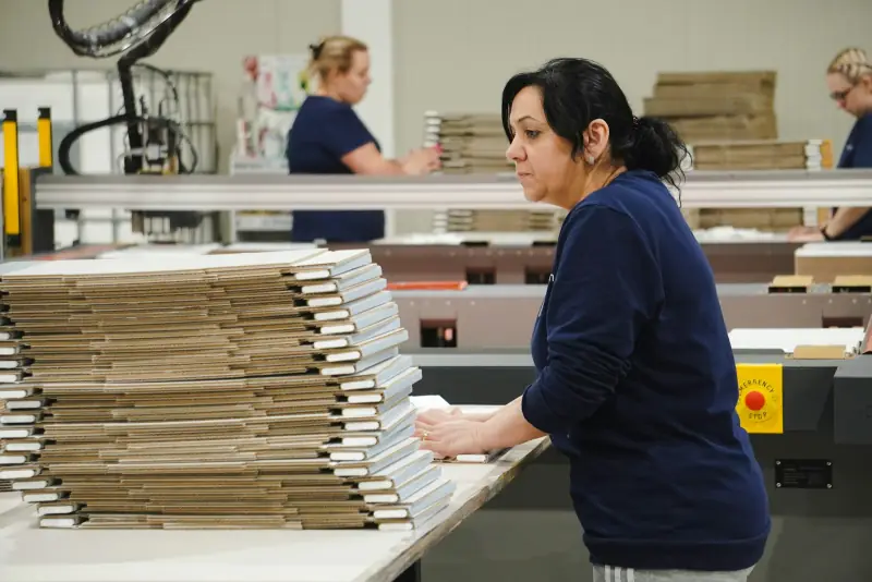 Trabajadora de una imprenta entre pilas de papel.